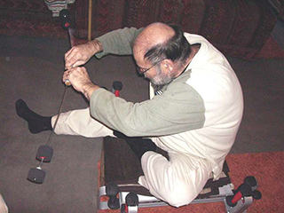 Stab waagrecht vor dem Oberkörper schwingen nach vorne gebeugt auf dem Posturomed sitzend